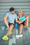 Modern couple making pause on the sidewalk during jogging / exercise.