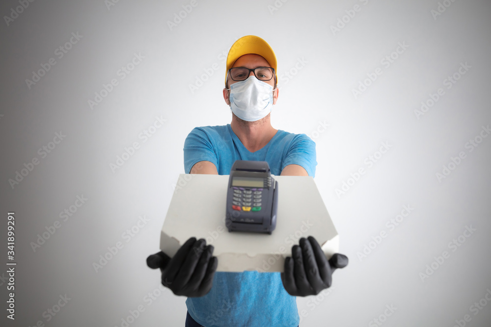 Delivery guy with protective mask holding pizza box and POS for contactless payment. Delivery guy with protective mask holding pizza box and POS for contactless payment.