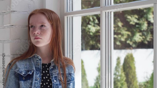 Bored child with sad eyes by window