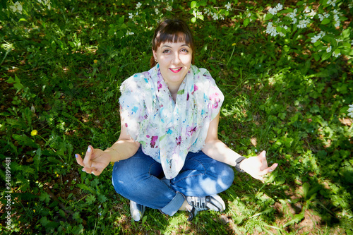 Portrait of an ugle fat chubby plump girl and blossoming apple tree with white flower background in the park in a spring time photo