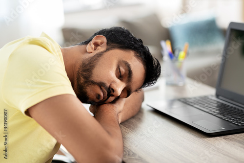 people and lifestyle concept - tired indian man sleeping on table with laptop computer at home