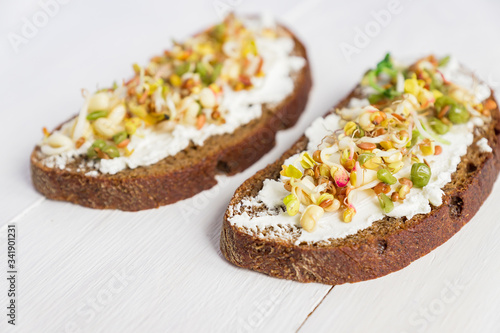 Close up of sandwiches on rye bread with cream cheese and sprouted mung beans, walnut, sunflower and flax. Macrobiotic healthy breakfast.