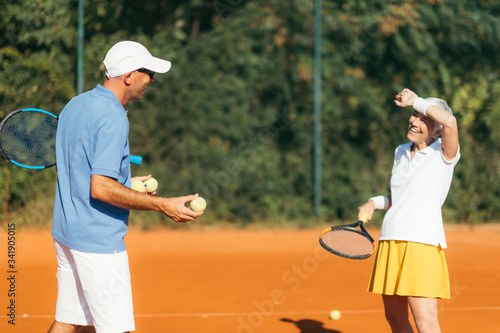 Tennis instructor with senior woman, tennis training lesson © Microgen