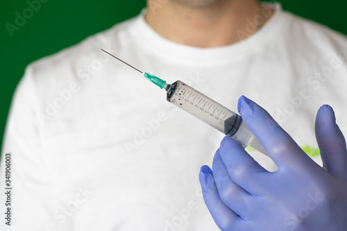 doctor in blue medical gloves holding syringe with needle closeup