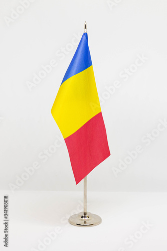 State desktop flag of Romania on metal flagpole isolated on white background. National symbol