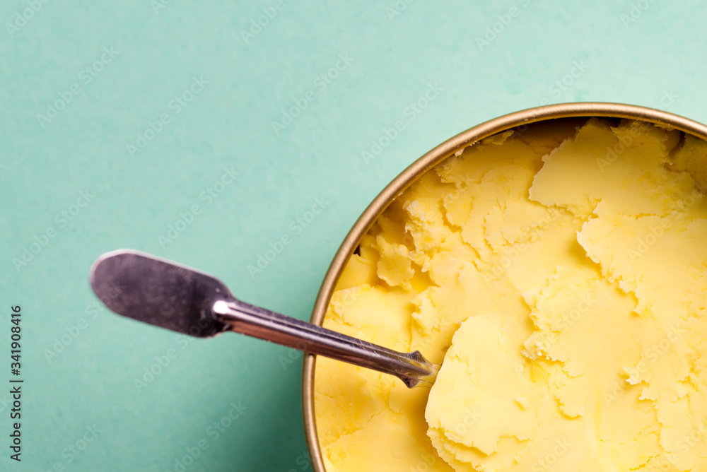 Close-up view of homemade fresh cold natural ice-cream light yellow color in a bowl with spoon on blue background. Close-up view of homemade fresh cold natural ice-cream light yellow color in a bowl with spoon on blue background.