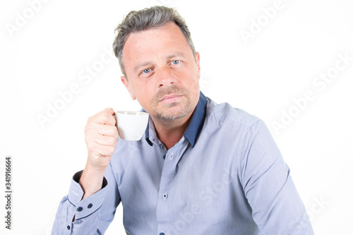 serious businessman handsome man wearing blue shirt drinking coffee from cup isolated over white background © OceanProd