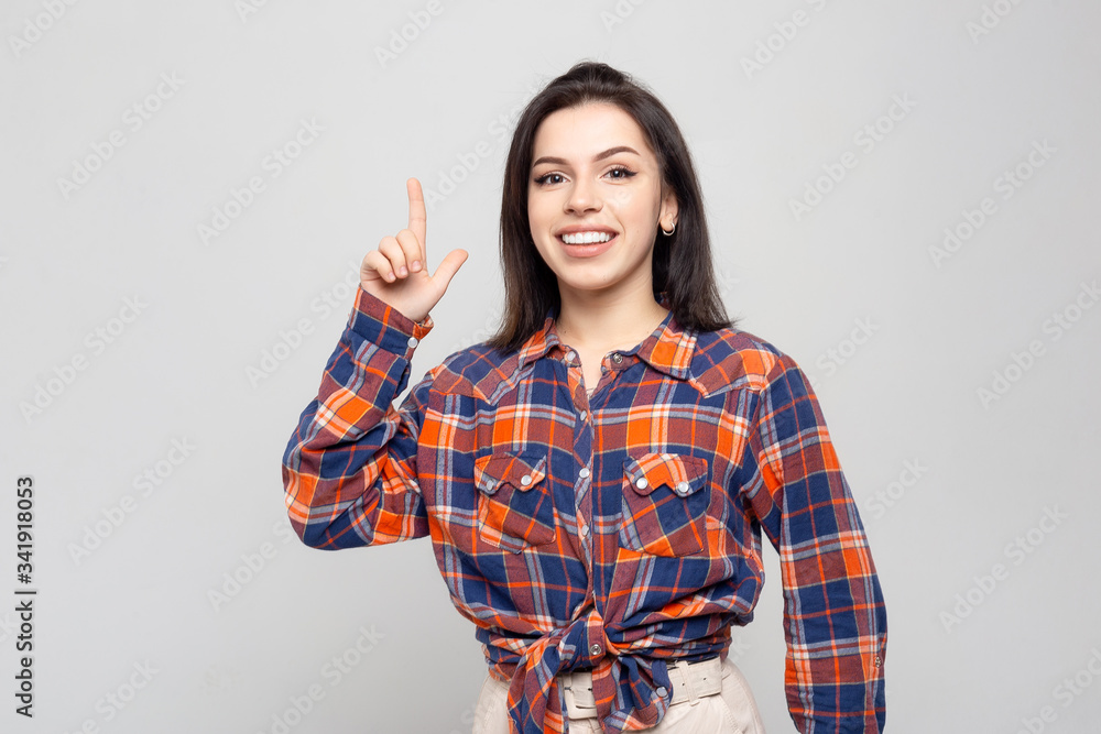 Portrait of a beautiful young woman thinking, isolated on white-gray background.Portrait of a beautiful smiling brunette in a plaid shirt came up with an idea, inspiration, mischief Portrait of a beautiful young woman thinking, isolated on white-gray background.Portrait of a beautiful smiling brunette in a plaid shirt came up with an idea, inspiration, mischief