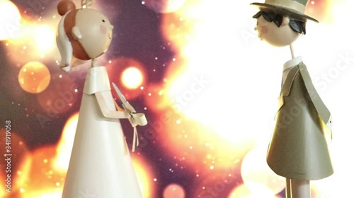 Two wedding toys, a groom and a bride, kissing on the special day of their marriage on a bokeh defocused light background
