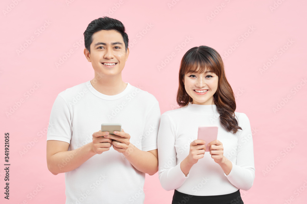 Image of asian man and woman using smartphones isolated over colorful background