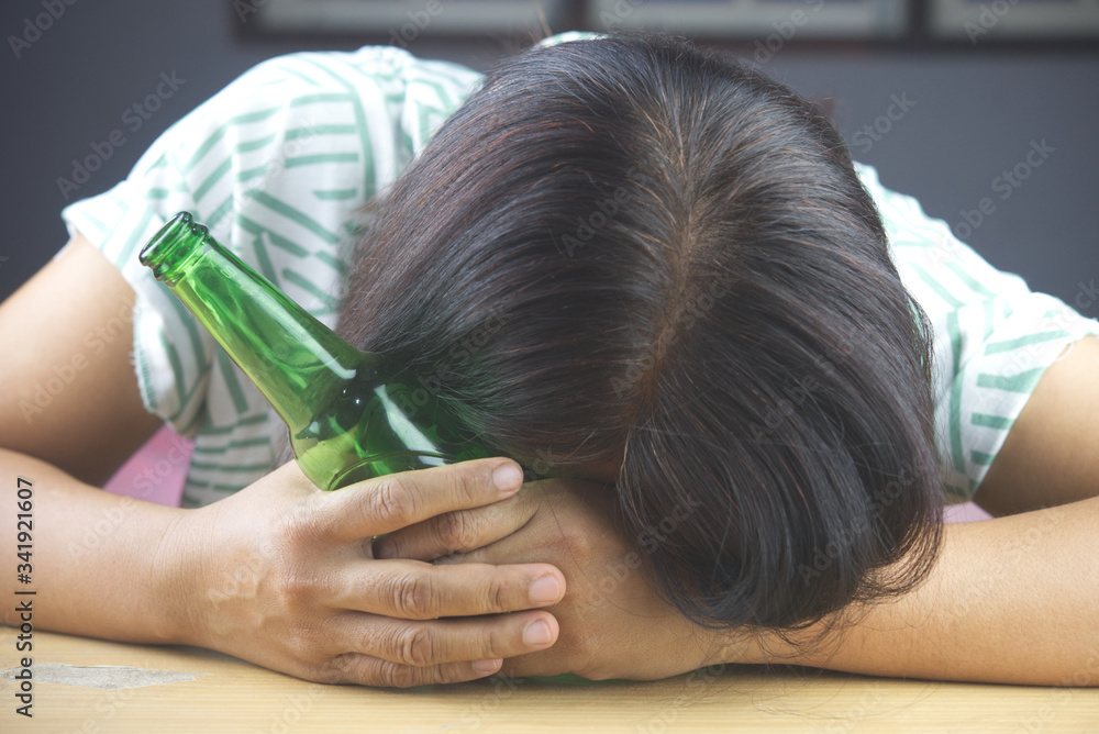 Bottle of Beer and background images in women headaches. The result of excessive alcohol consumption. Bottle of Beer and background images in women headaches. The result of excessive alcohol consumption.