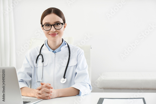 Portrait of young female doctor in white coat at workplace