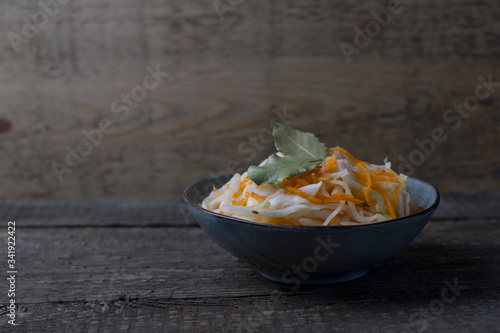 fermented white cabbage on a gray plate on a wooden background.