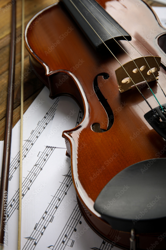 Fototapeta premium Beautiful violin, bow and note sheets on wooden table