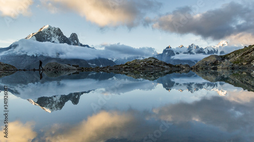 silouhette of man walking along a lake with reflexion of mountains in Mont-Blanc mountain range