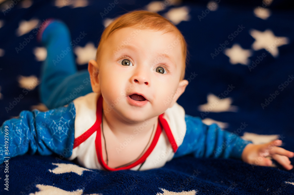little boy lies on a blue background with stars
little boy lies on a blue background with stars