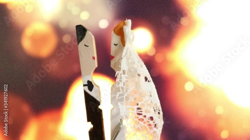 A clothespin hand painted as a groom and a bride kissing on the special day of their wedding on a bokeh defocused light background
