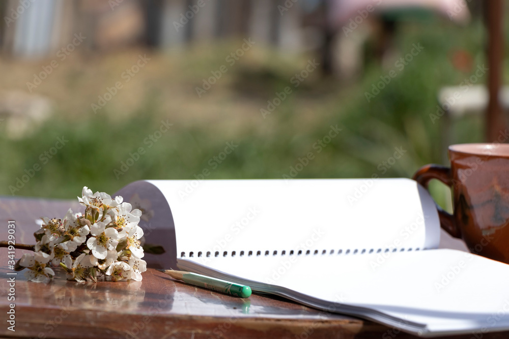 Spring flowering in a mug on a wooden background. Beautiful floral background. Notebook and pencil for drawing. Spring flowering in a mug on a wooden background. Beautiful floral background. Notebook and pencil for drawing.