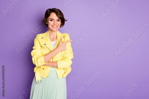 Portrait of positive cheerful girl promoter point index finger copyspace indicate ads promotion demonstrate sales feedback wear good look clothes isolated over violet color background