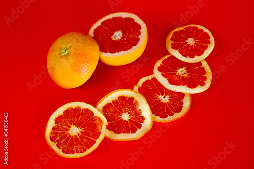 Chips of dried grapefruit sliced in thin circles  shot on a red background. Background for vegetarianism  healthy and wholesome food.