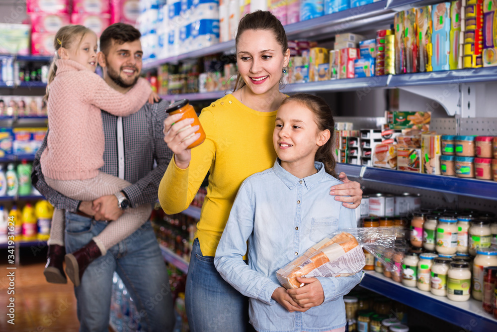 Happy family with two little girls buying food products in supermarket