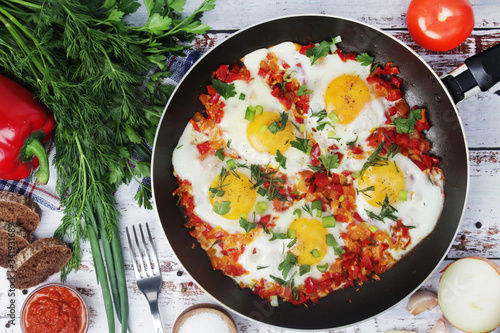 Shakshouka with five cooked eggs on top of tomato sauce in cast iron skillet