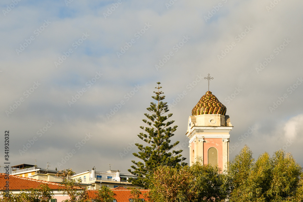 Obraz premium Top of the bell tower of the little church of Saint Joseph in the coastal town of Arma di Taggia against cloudy sky, province of Imperia, Riviera of Flowers, Liguria, Italy
