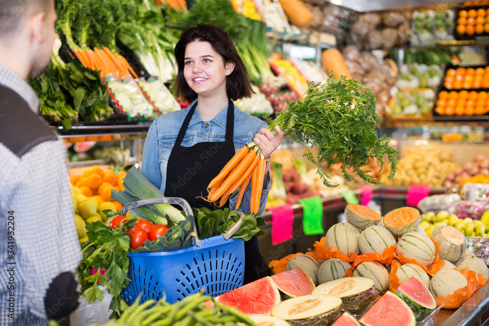 calm female seller assisting customer to buy fruit and vegetables in grocery shop