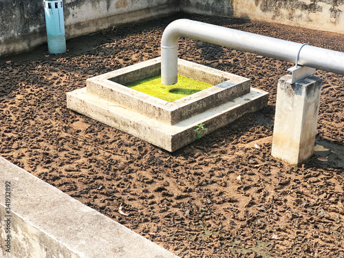 Sludge treatment in wastewater management system, flowing brown smelly liquid and drying in sludge bed, made it for fertilization can use in agriculture field. Cement and concrete well background.