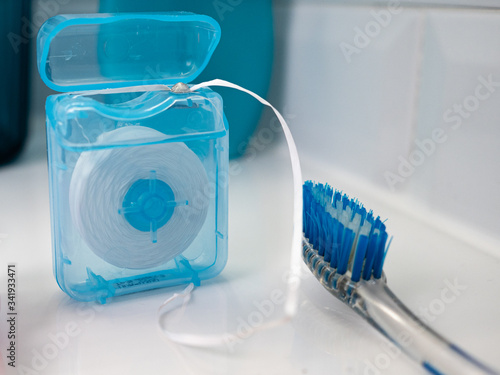 OPEN FLOSS ROLL AND BLUE TOOTHBRUSH, IN THE BATHROOM