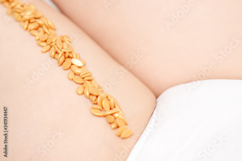 Wax beans on woman's leg in row. Concept of depilation and epilation.