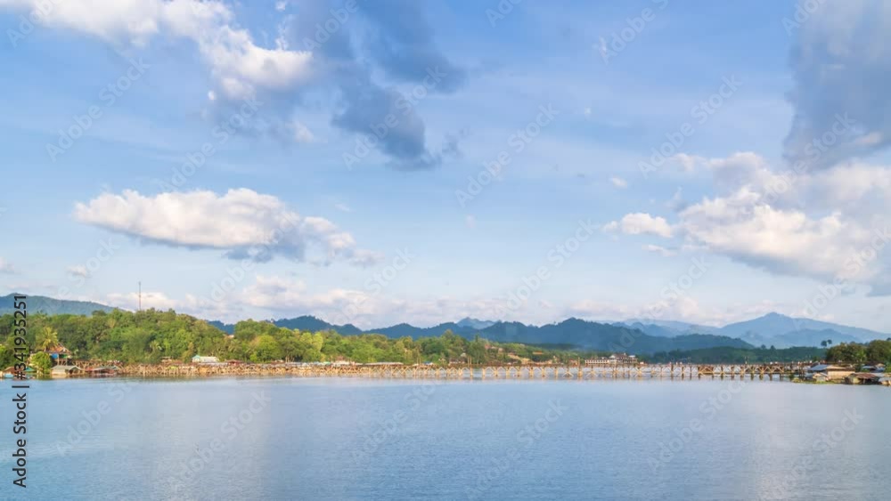 Mon Bridge, longest wooden bridge in country over Songalia River and reservoir over dam in Sangkhlaburi during sunny day, Kanchanaburi, Thailand; zoom in - Time Lapse Mon Bridge, longest wooden bridge in country over Songalia River and reservoir over dam in Sangkhlaburi during sunny day, Kanchanaburi, Thailand; zoom in - Time Lapse