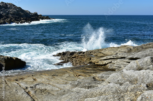 Summer landscape with wild waves breaking against the rocks and blue sky. Spain. 