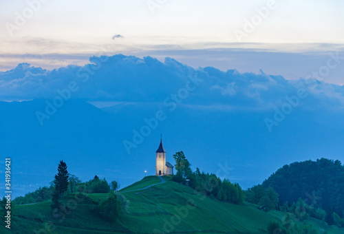 Charming little St. Primus and Felician church in Jamnik, Julian Alps, Slovenia and beautiful sunrise sky colors