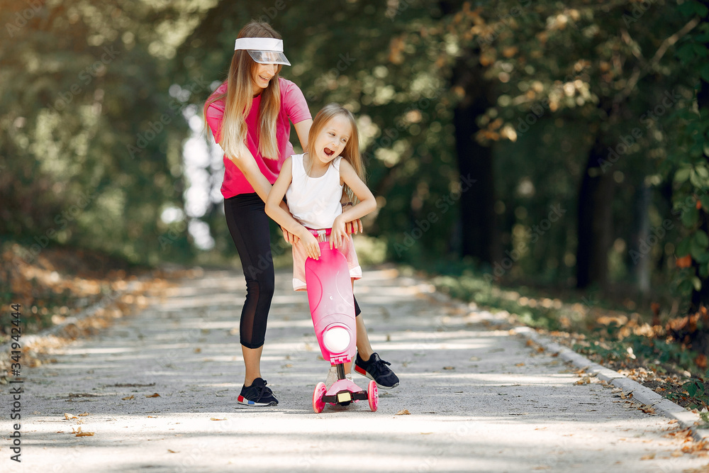 Family in a summer park. Mother in a pink t-shirt. Cute little girl Family in a summer park. Mother in a pink t-shirt. Cute little girl