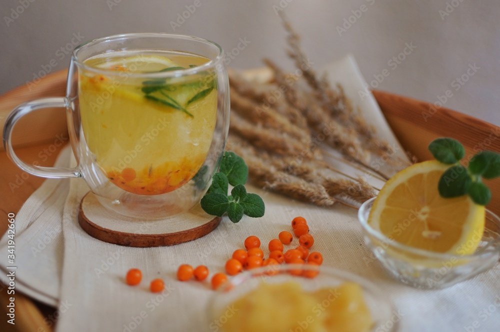 A cup of sea buckthorn tea with mint, lemon and honey with rustic background A cup of sea buckthorn tea with mint, lemon and honey with rustic background