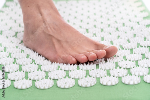 Foto Female foot on an acupuncture rug