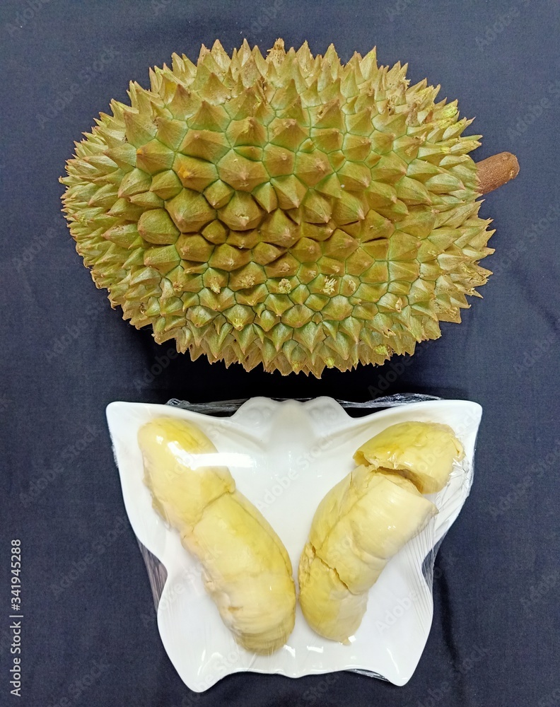 Durian and peeled raisins contained in a white plate on a black background Durian and peeled raisins contained in a white plate on a black background