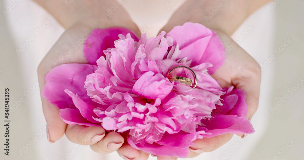 wedding couple are holding rose petals and wedding rings in hands