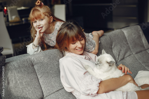 Beautiful mother with little daughter. Family sitting in the room. Woman playing with a kitty