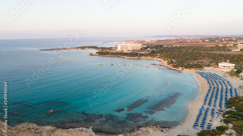 Aerial bird's eye view of Landa beach, Ayia Napa, Famagusta, Cyprus. Landmark tourist attraction golden sand bay at sunrise with boats anchored between Makronissos and nissi in Agia Napa, from above. 