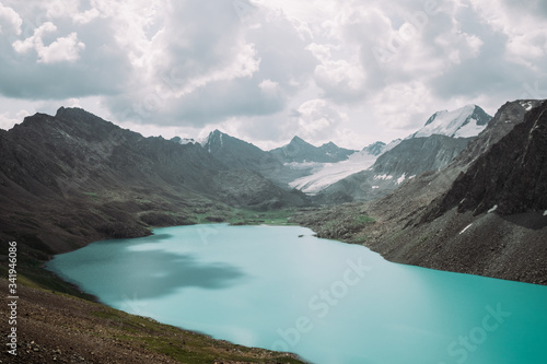 Kyrgyzstan. Karakol. Alakel. A beautiful alpine lake of turquoise color among high snow-capped mountains. Summer