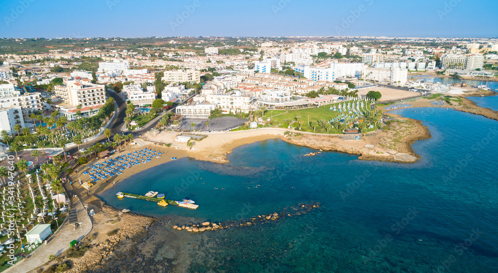 Aerial bird's eye view Pernera beach Protaras, Paralimni, Famagusta, Cyprus. The tourist attraction golden sand bay with sunbeds, water sports, hotels, restaurants, people swimming in sea from above.