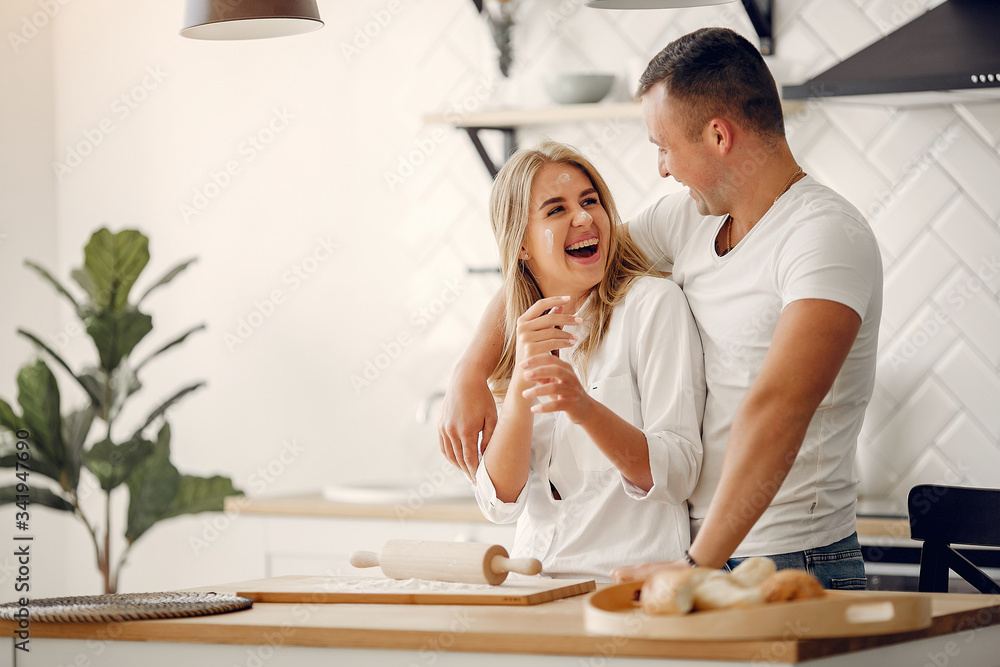 Couple in a kitchen. Blonde in a white shirt. Woman with her husband Couple in a kitchen. Blonde in a white shirt. Woman with her husband