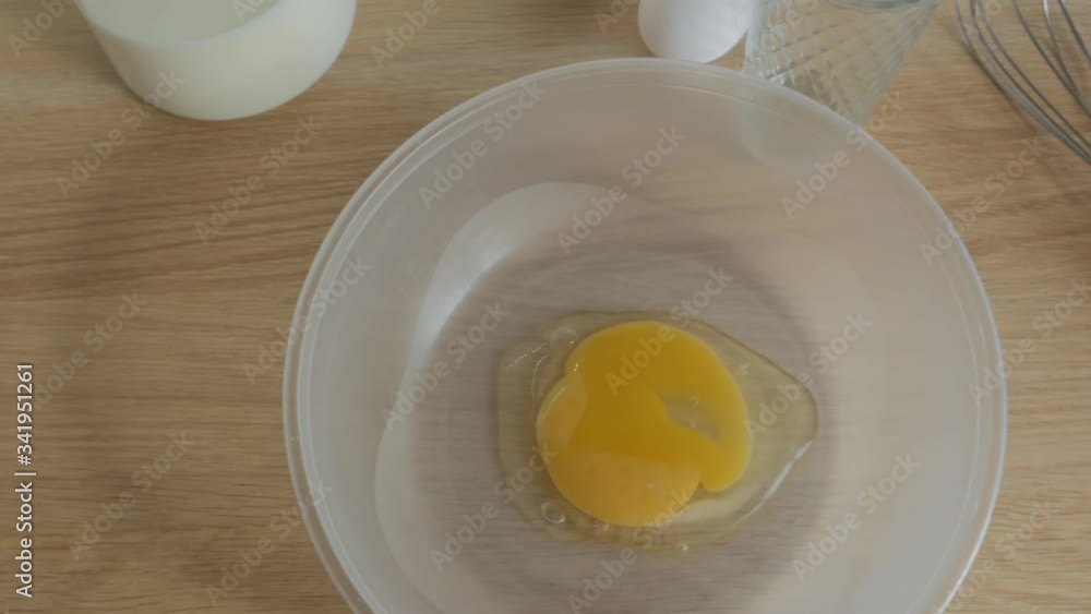 A male cook breaks eggs in a bowl and turns out a smiley face of egg yolks. The view from the top. 4K. Smile of the broken eggs. Cooking pancakes A male cook breaks eggs in a bowl and turns out a smiley face of egg yolks. The view from the top. 4K. Smile of the broken eggs. Cooking pancakes