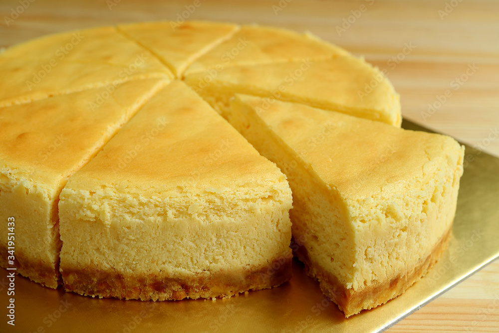Closeup a slice of creamy yellow plain baked cheesecake cut from the whole cake Closeup a slice of creamy yellow plain baked cheesecake cut from the whole cake