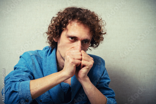 curly-haired man praying, clasped his hands together