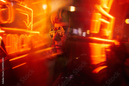 Woman with fringe wearing sunglasses with orange yellow red neon lights