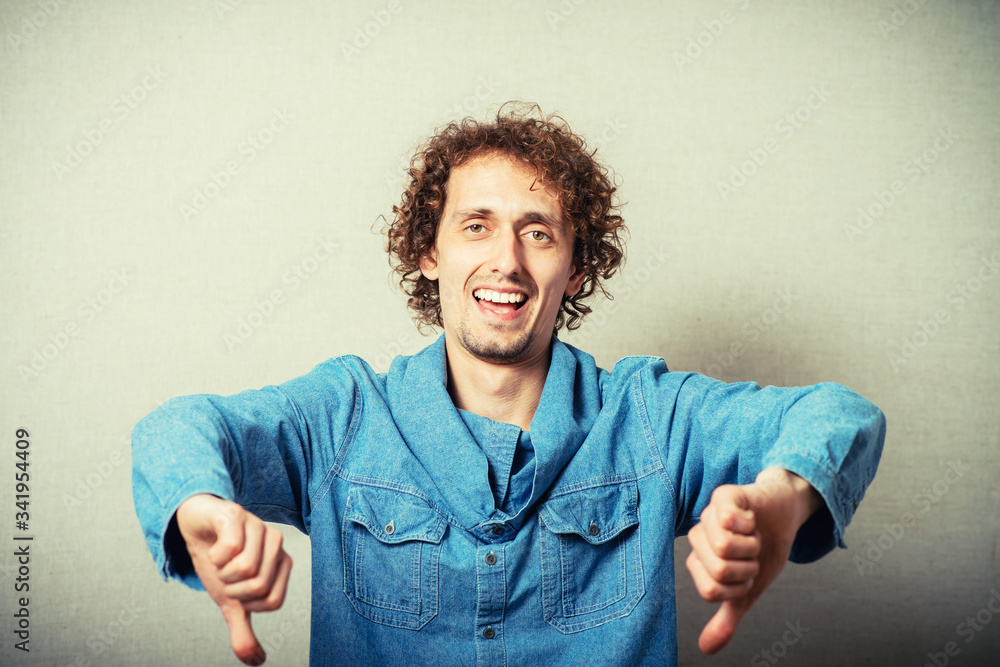 curly-haired man showing thumbs down curly-haired man showing thumbs down