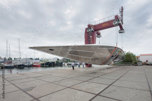 Shipyard. Shipbuilding industry. Aluminium hull. Turning of the hull. Crane.
